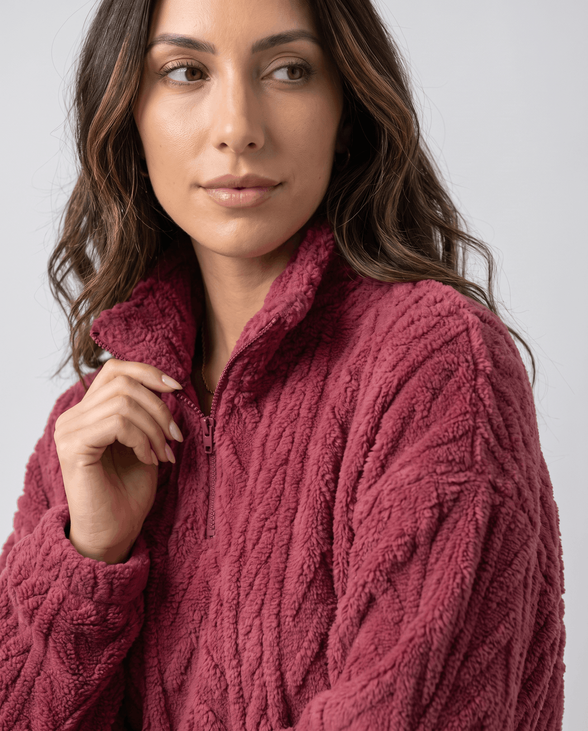 Model touching the zipped collar of a burgundy plush quarter-zip