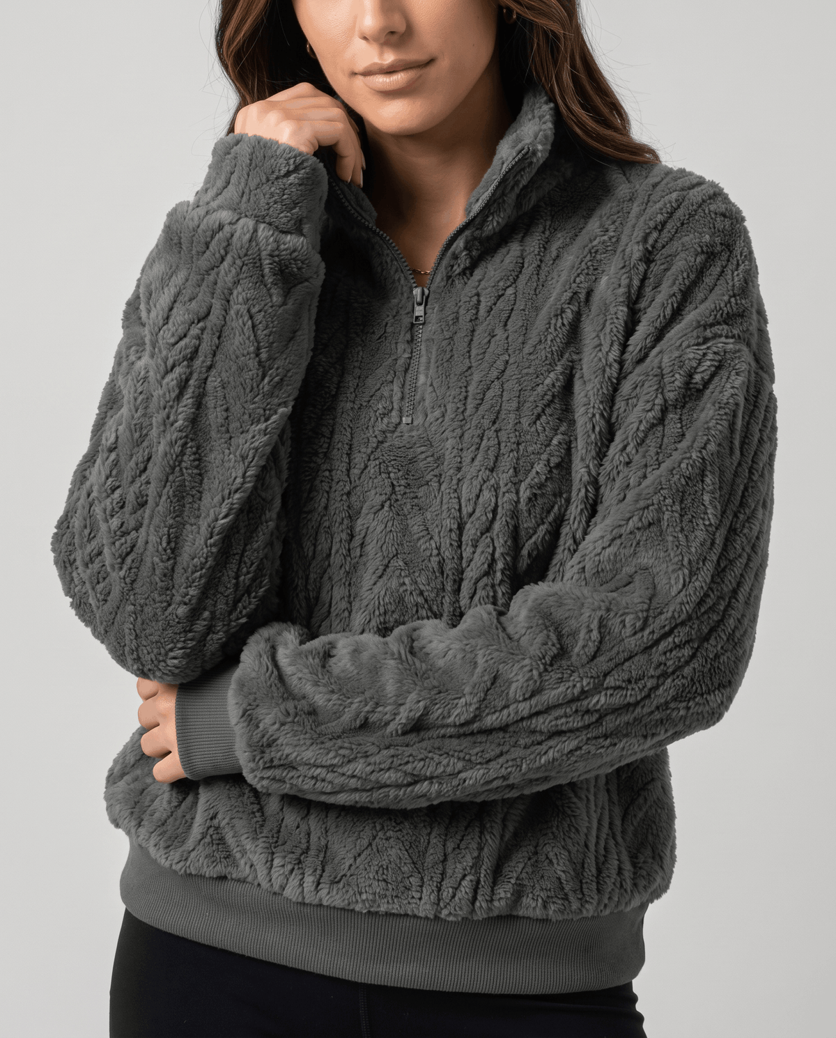 Model adjusting the collar of a dark gray cable-textured quarter-zip