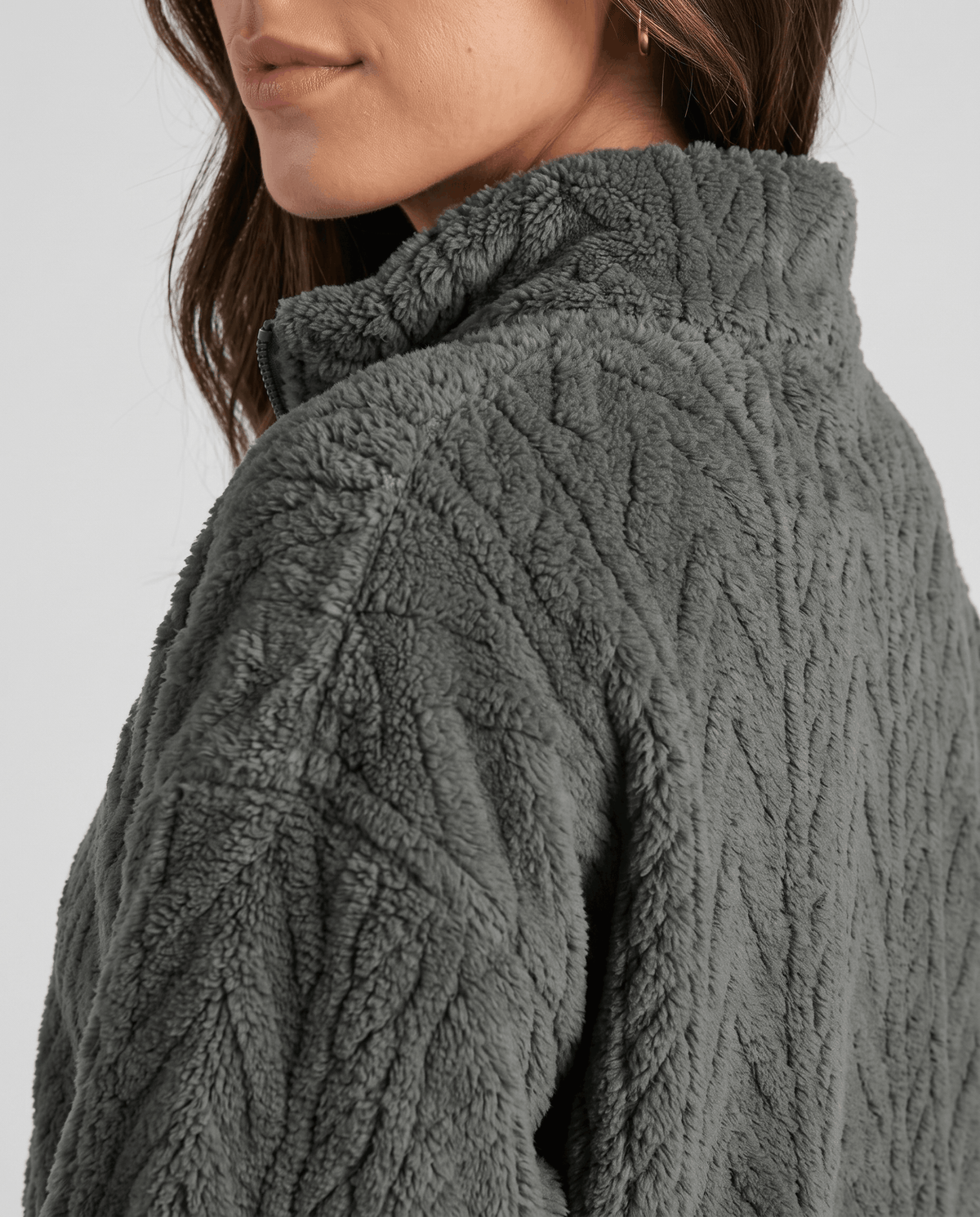 Shoulder detail of dark gray plush knit showing stand collar and cables