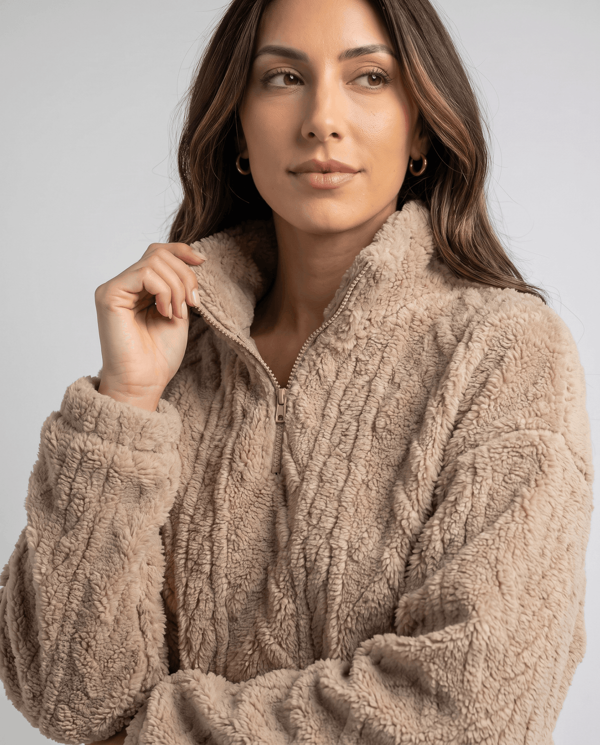 Close-up of model touching the collar of a khaki plush quarter-zip