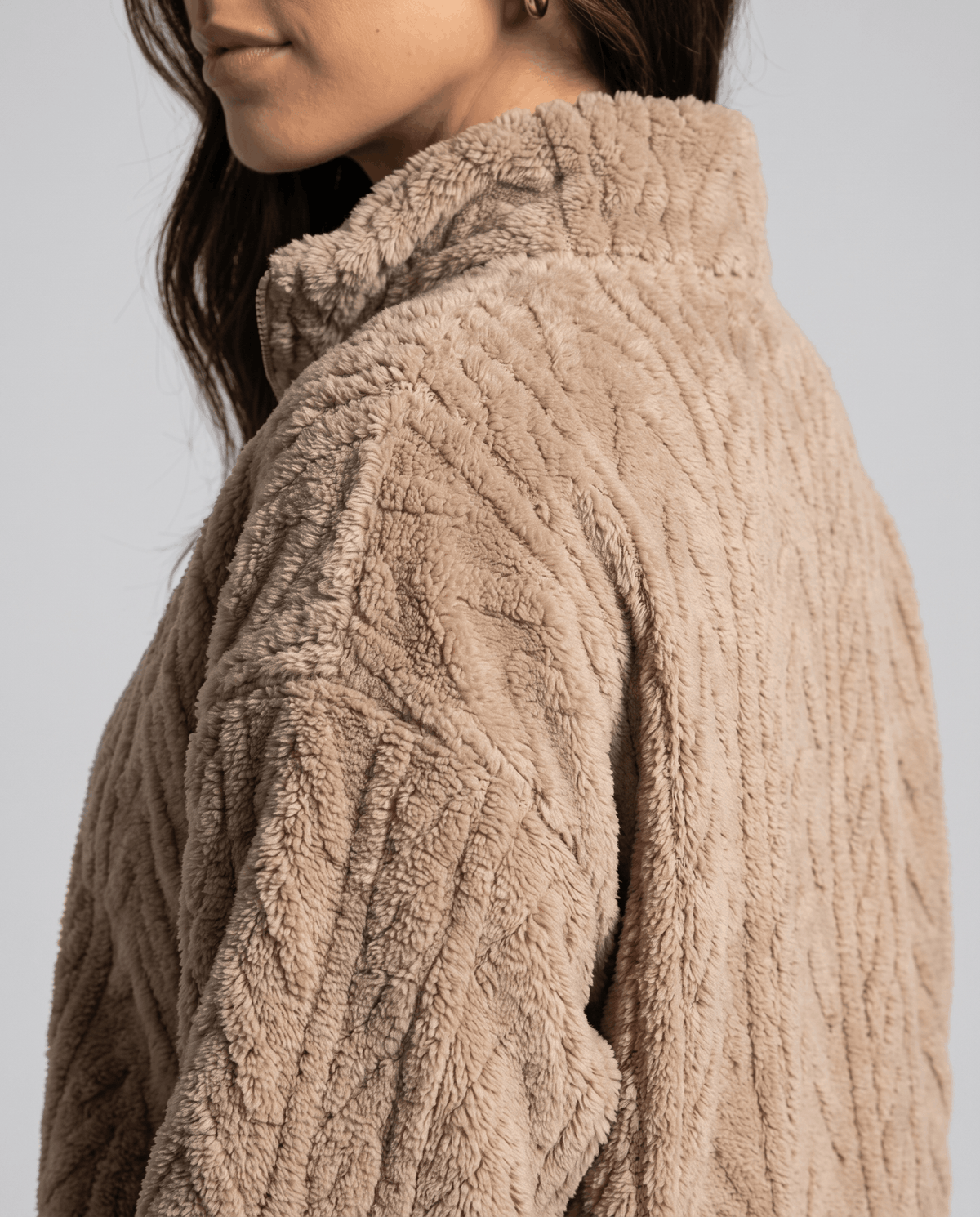 Side shoulder detail of khaki fleece showing embossed cable texture