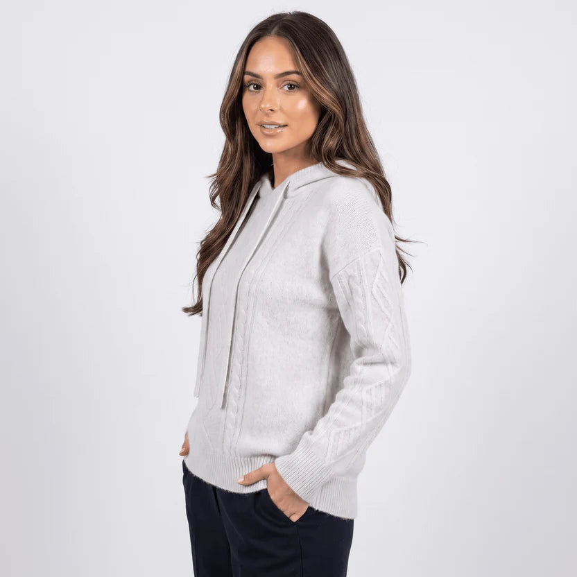 Three-quarter view of model in light gray hooded sweater with hand in pocket