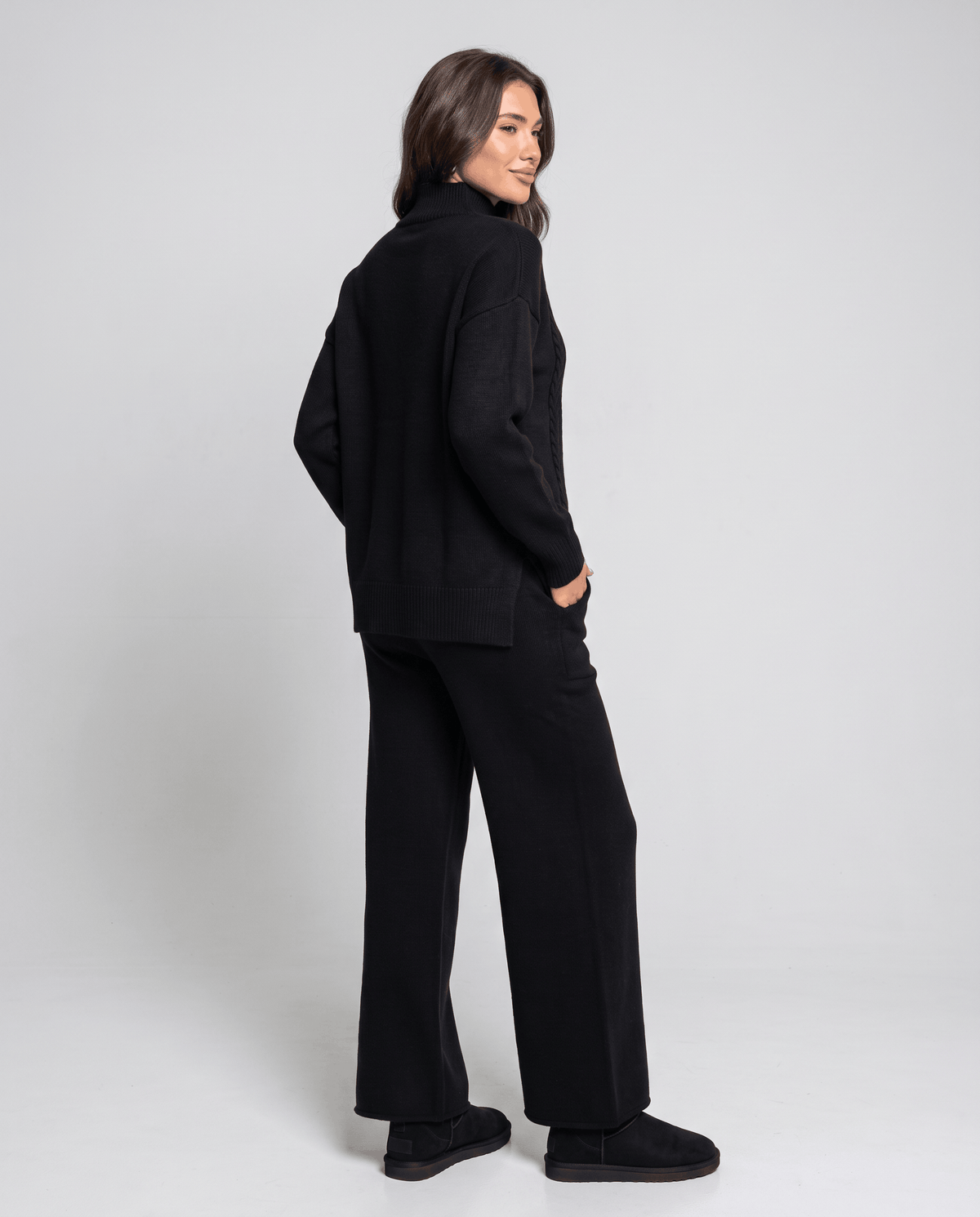 Back view of the black cable knit pullover and wide-leg pants