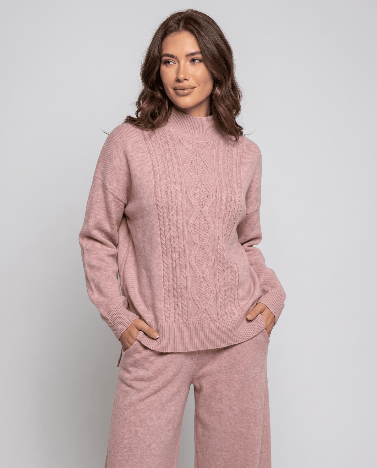 Pink cable knit pullover with a loose, relaxed shape, three-quarter view