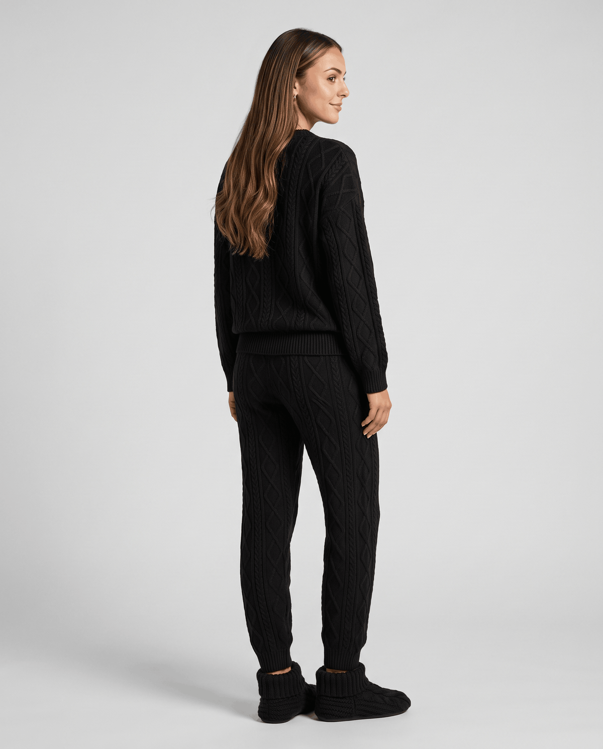 Back view of woman in black cable knit sweater and jogger pants