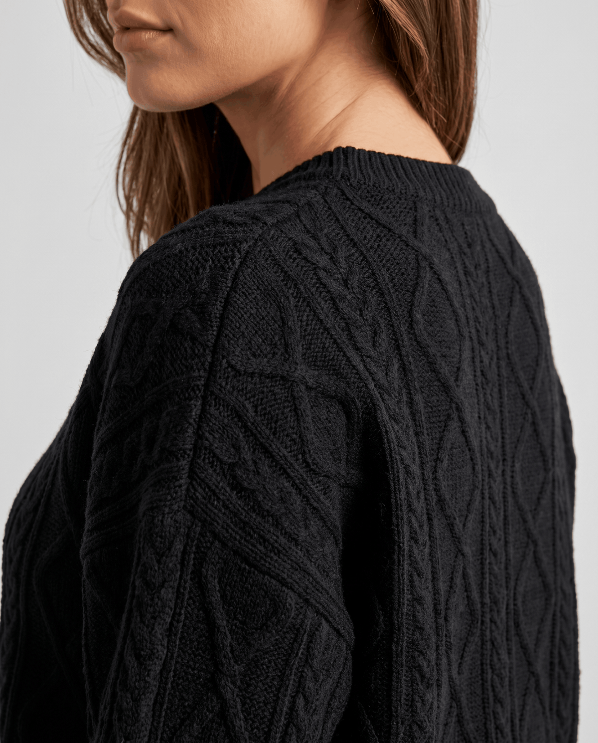 Detail of black cable knit pattern on the sweater shoulder and sleeve