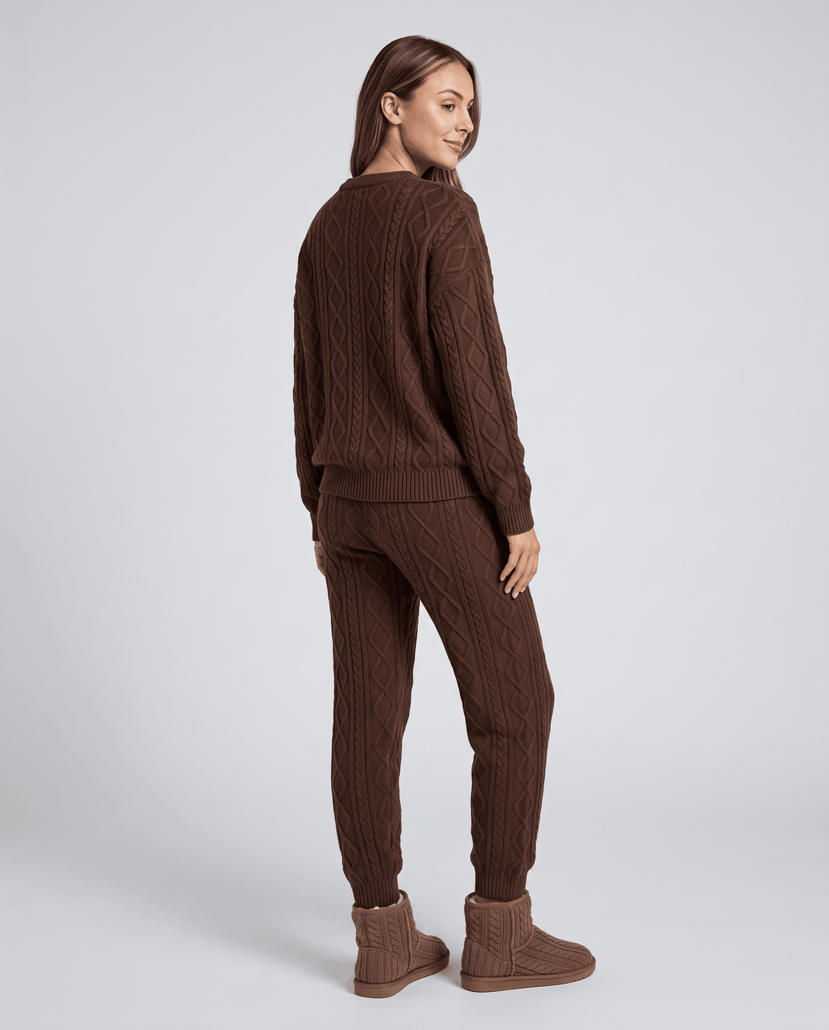 Back view of woman in brown cable knit sweater and jogger pants