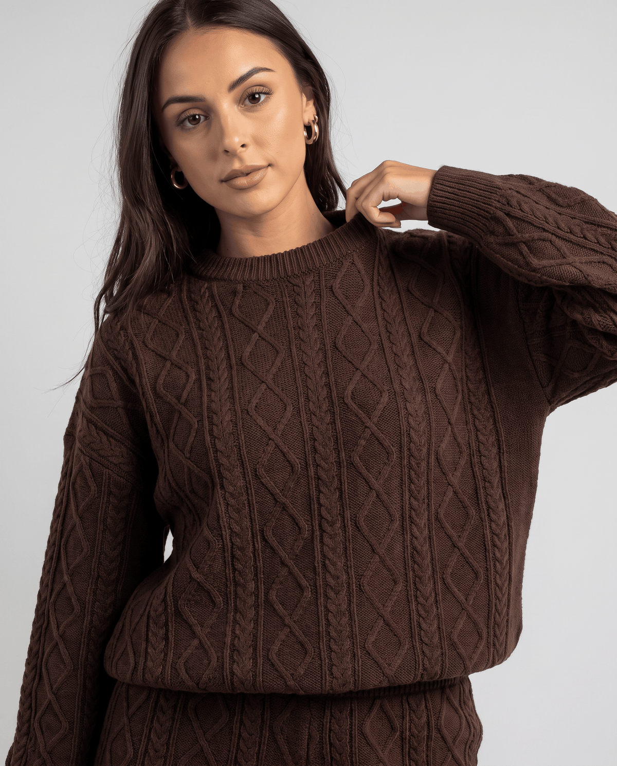 Close-up of brown cable knit crew neck sweater texture on a woman