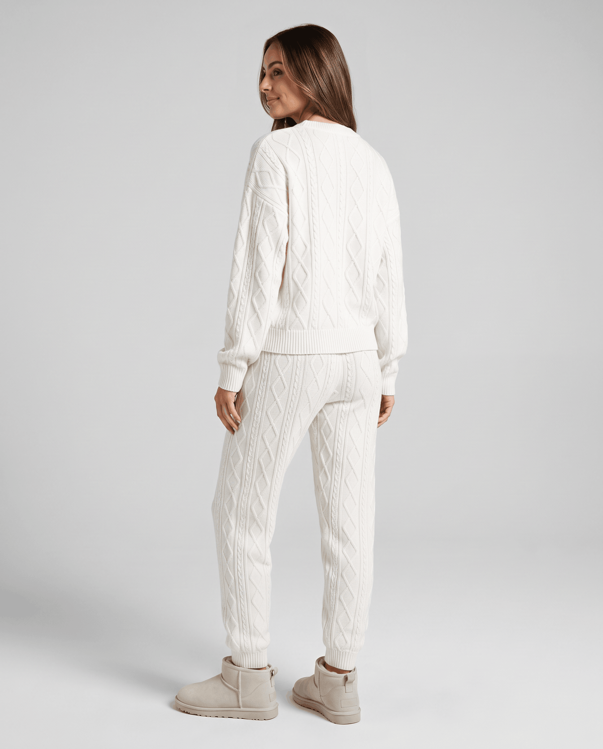 Back view of woman in cream cable knit sweater and jogger pants