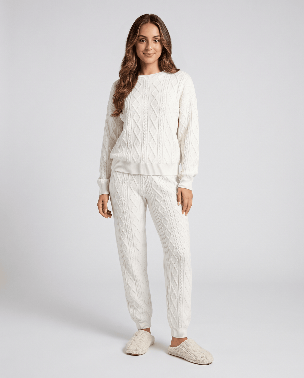 Front view of woman in cream cable knit sweater and matching joggers