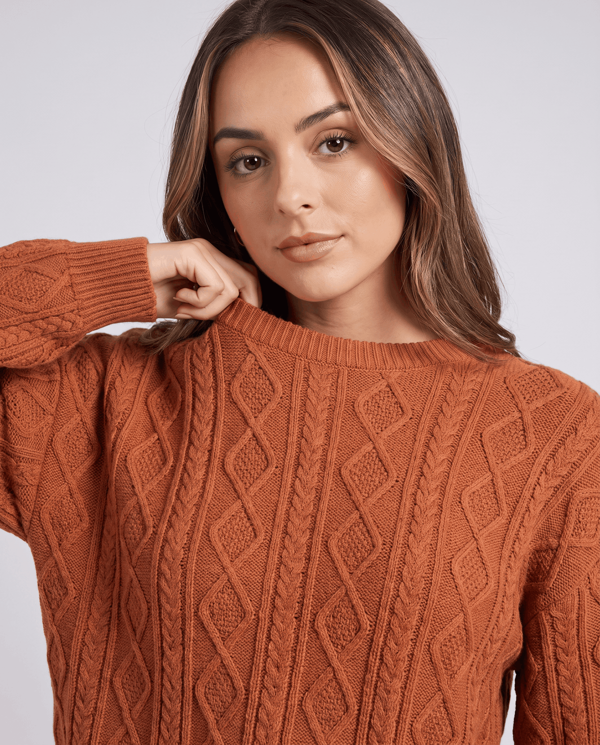 Close-up of orange cable knit crew neck sweater and long sleeve