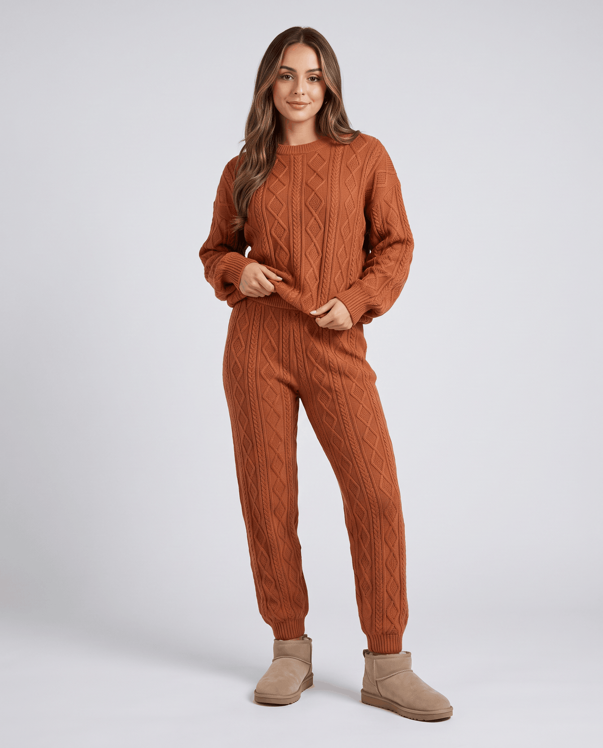 Woman wearing an orange cable knit sweater and matching jogger pants
