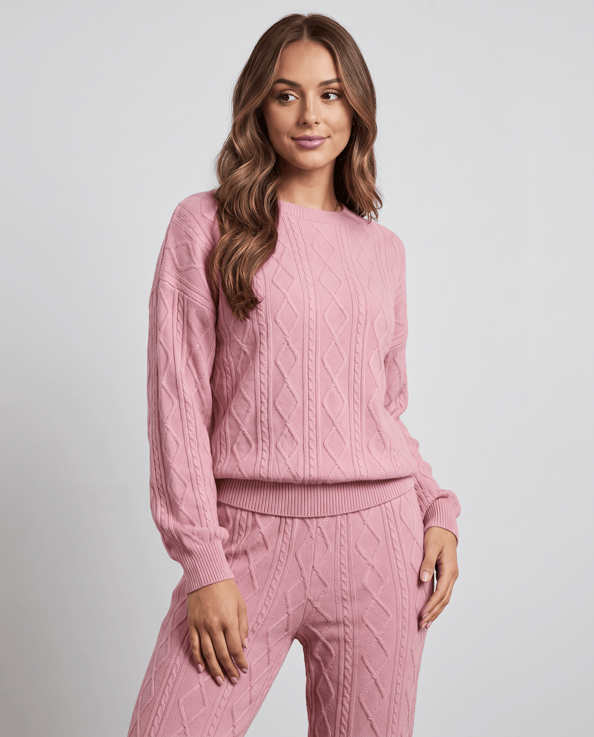 Close-up of pink cable knit crew neck sweater worn with matching pants