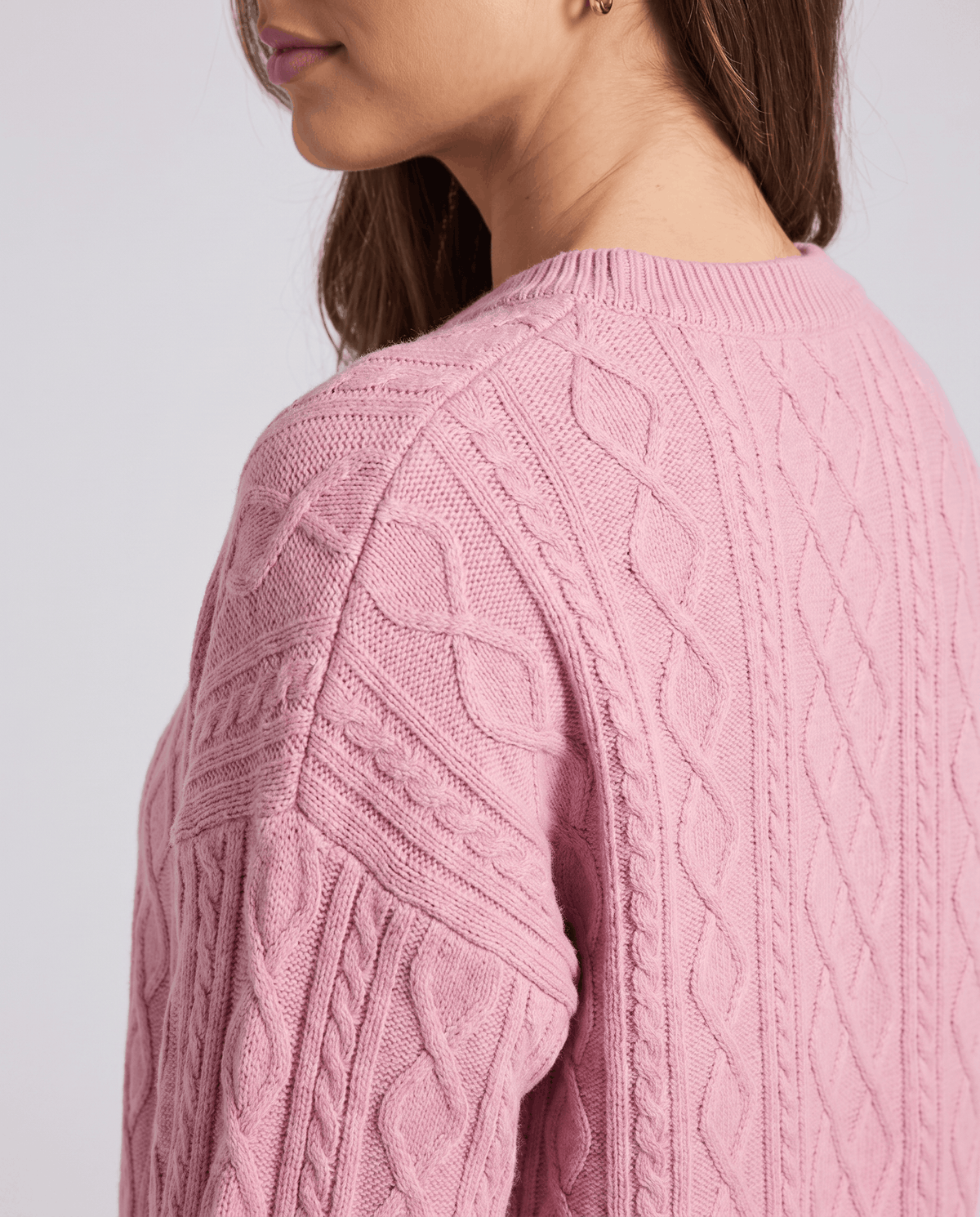 Detail of pink cable knit pattern on the sweater back and sleeve