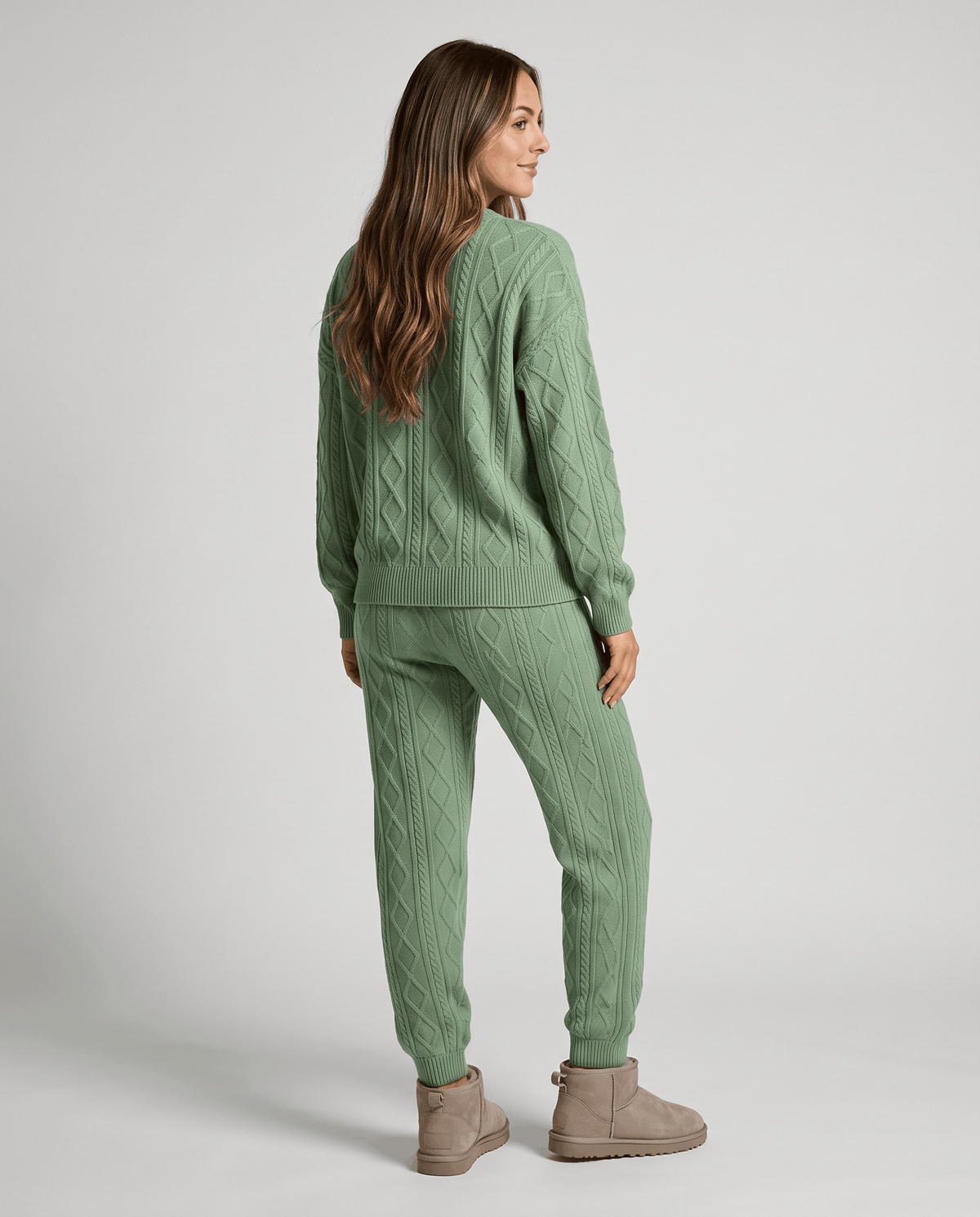 Back view of woman in sage green cable knit sweater and jogger pants