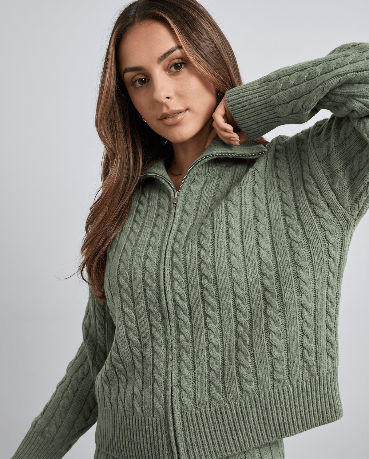 Close-up of the cable-knit pattern on the sage green zip-up jacket