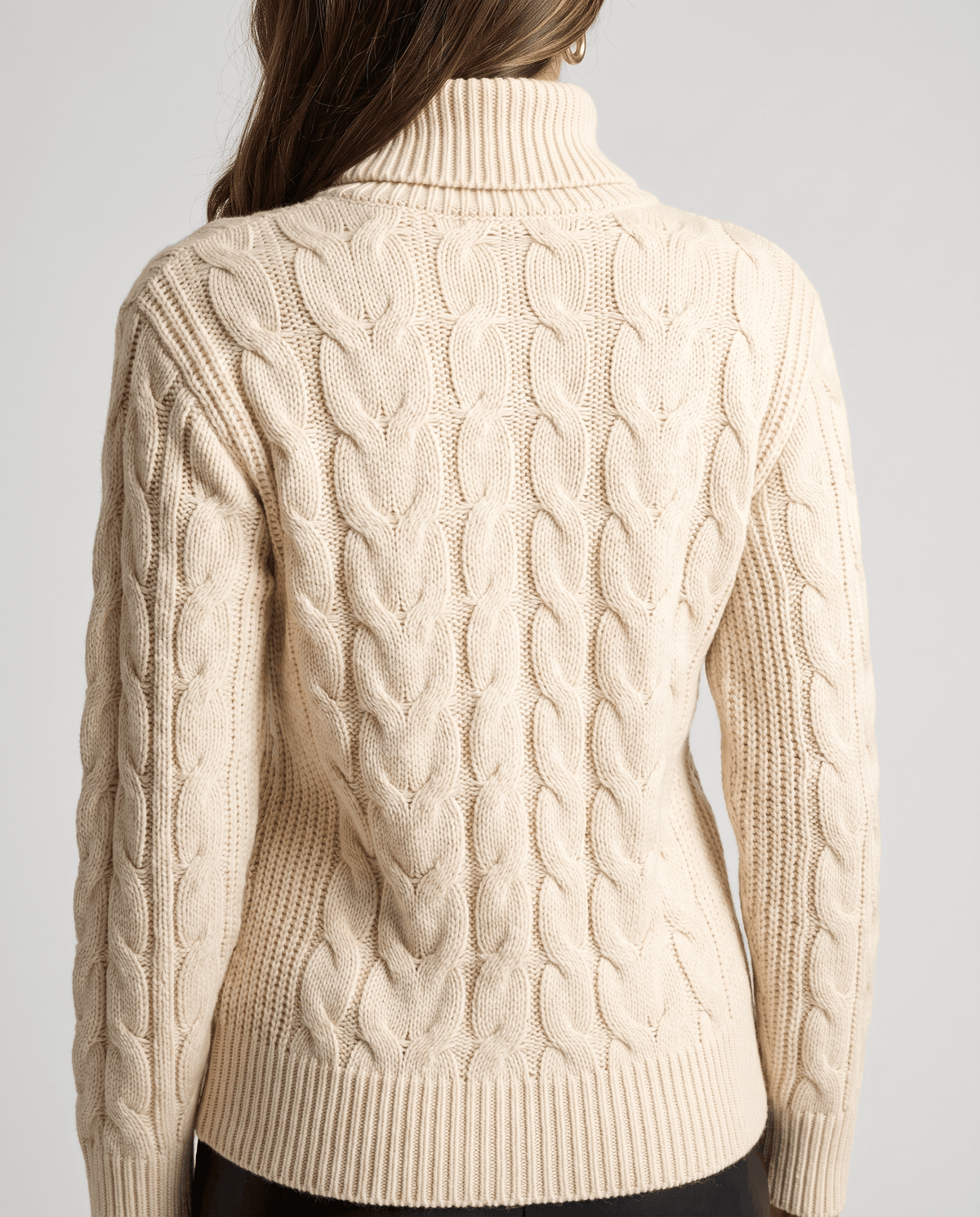 Back of the beige sweater showing vertical cables and a ribbed waistband