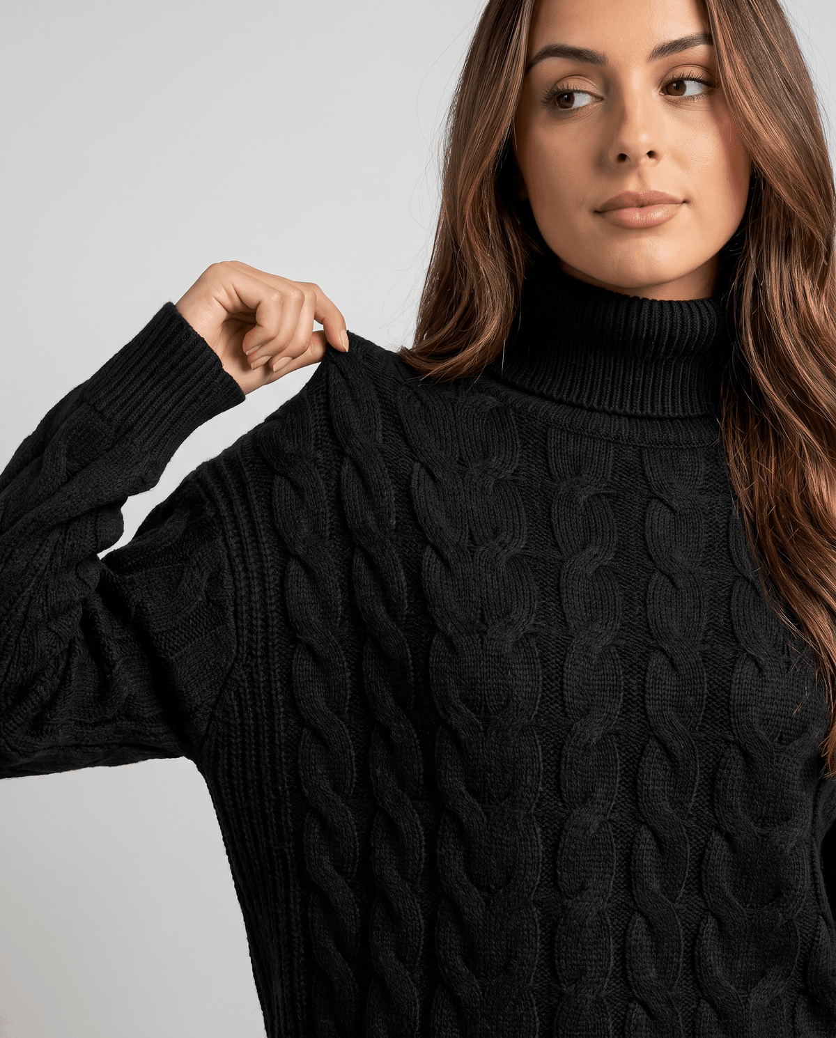 Close-up of black cable texture on the sleeve as she adjusts the shoulder