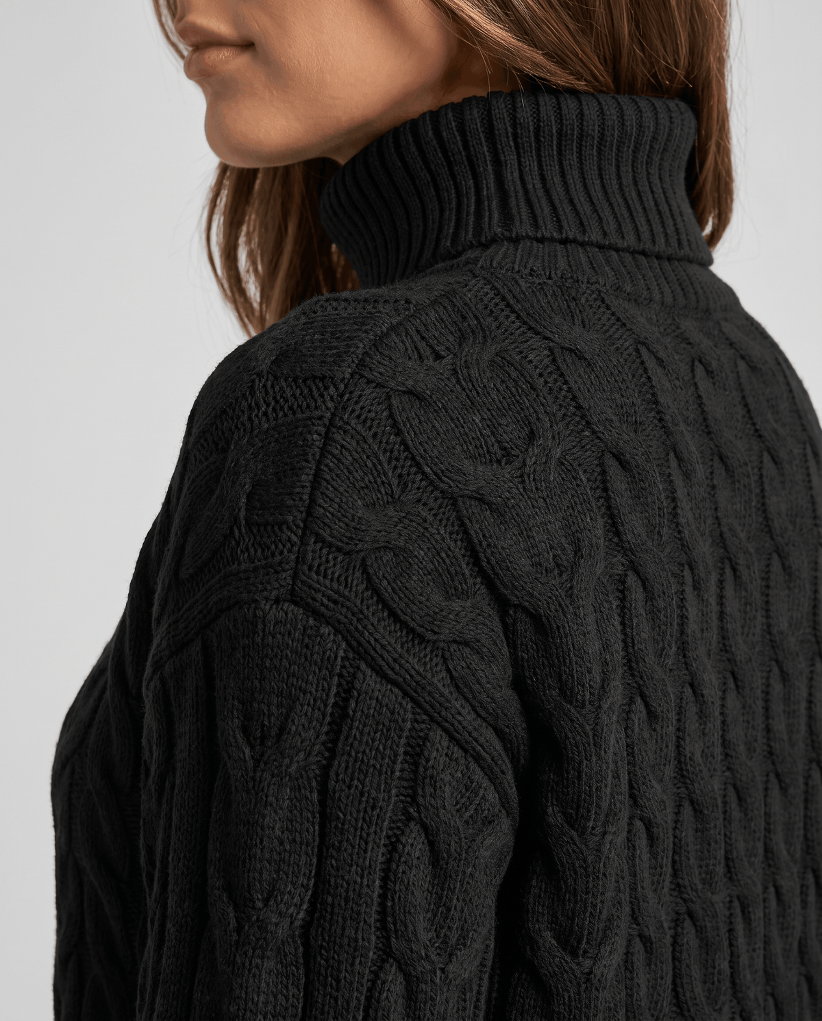 Side detail of the black ribbed turtleneck collar and shoulder cable pattern
