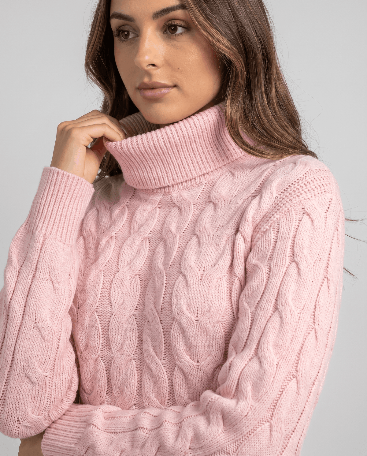 Close-up of pink twisted cables and fold-over neck as she touches the collar
