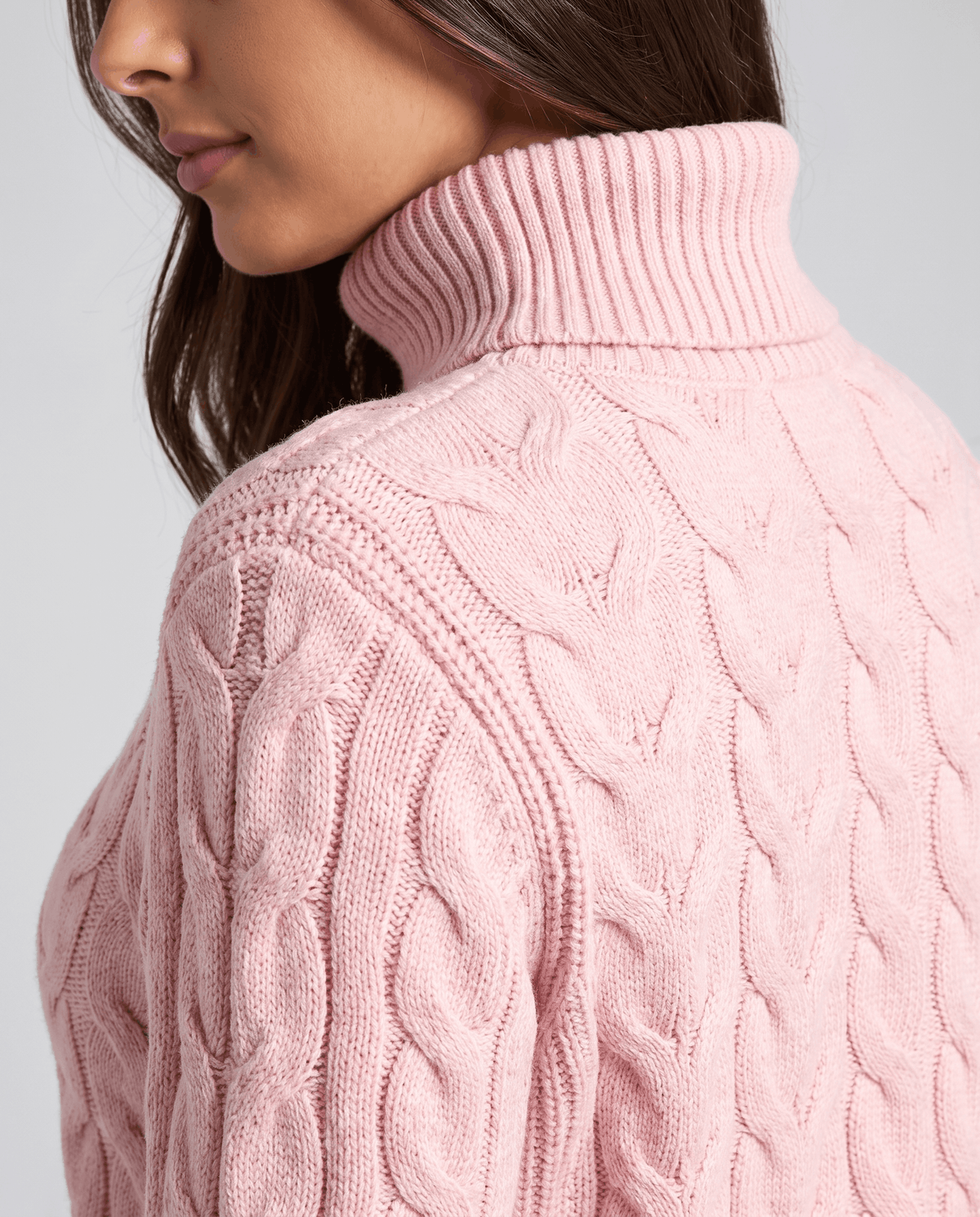 Side view of the pink sweater showing the tall ribbed collar and shoulder cables