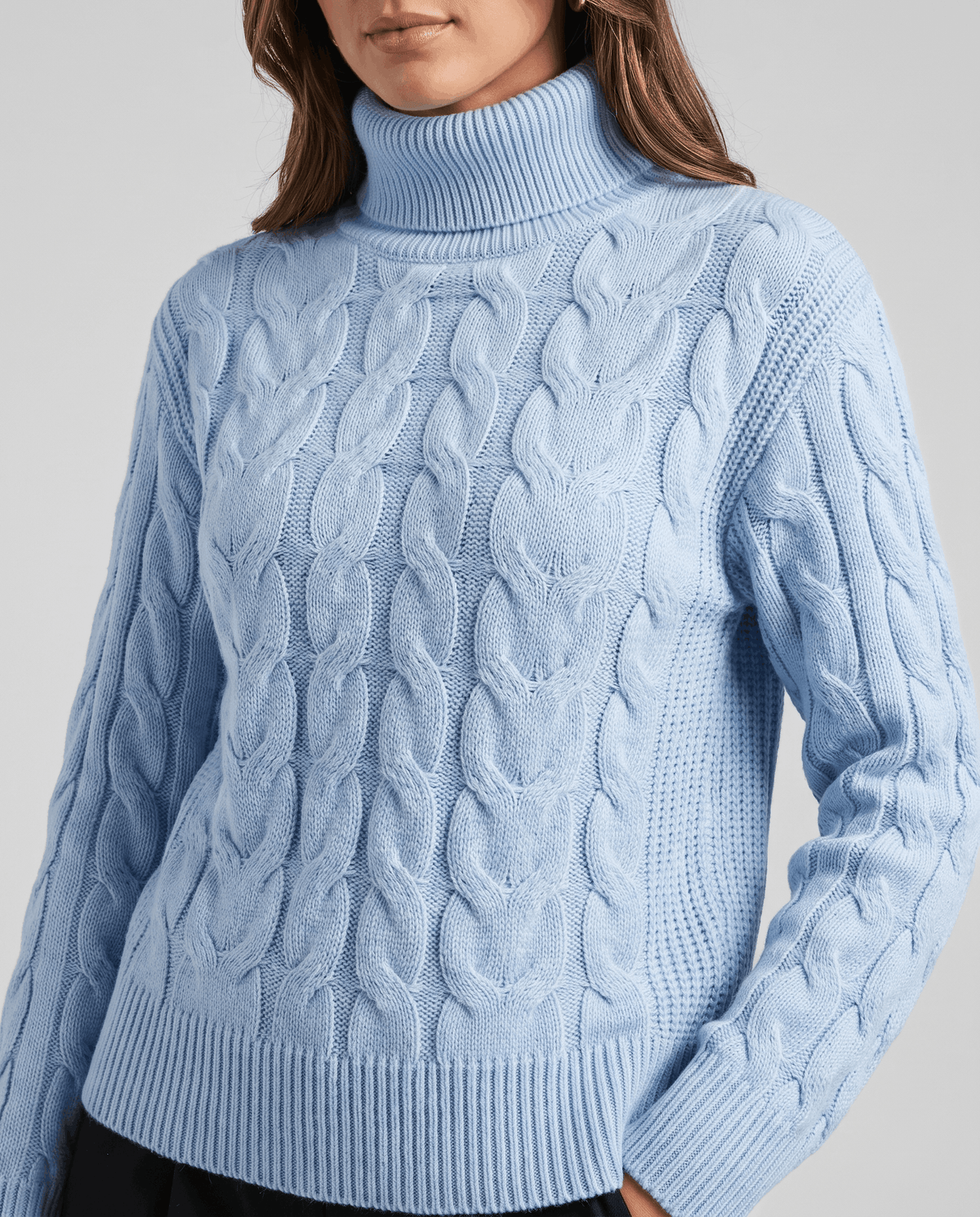 Front close-up of the sky blue sweater with raised cables and ribbed cuffs
