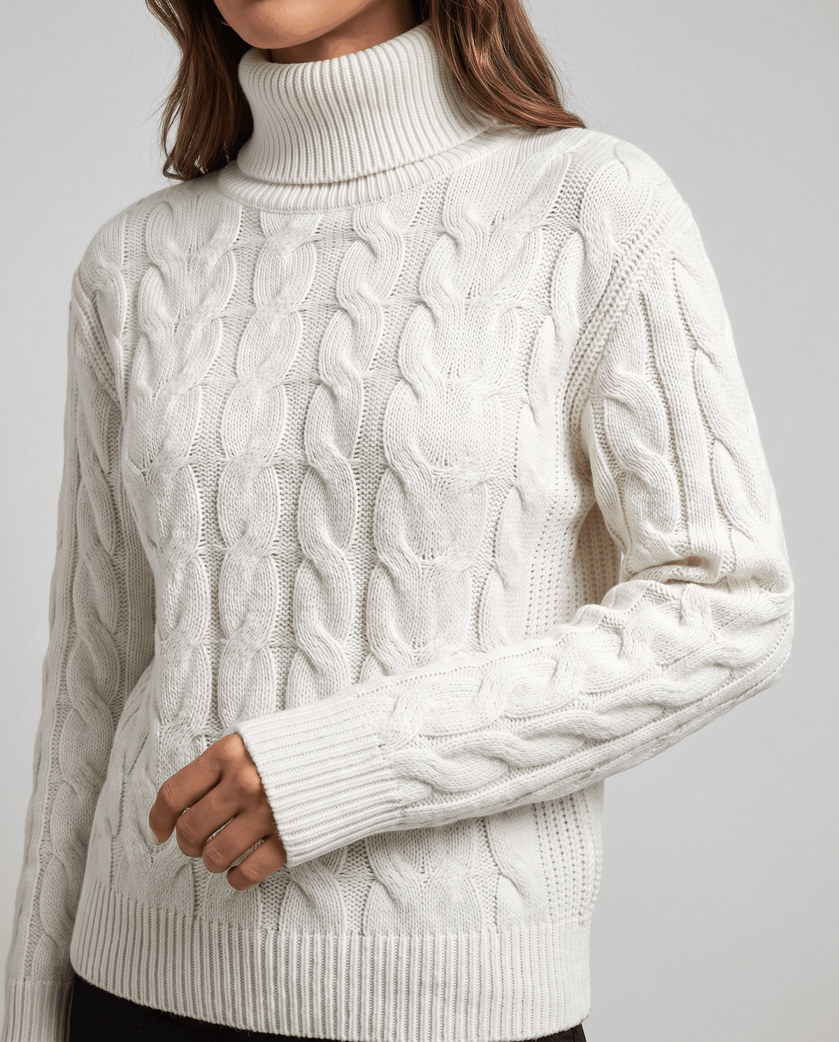 Front close-up of the white sweater showing braided cables and ribbed cuffs
