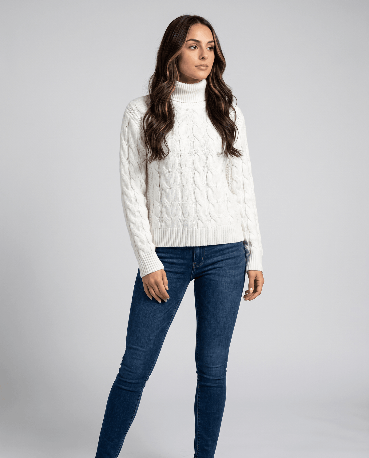 Standing full-length view in the white turtleneck with slim blue jeans