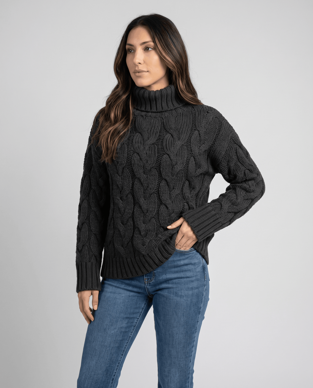 Front view of charcoal black cable knit turtleneck worn with light jeans