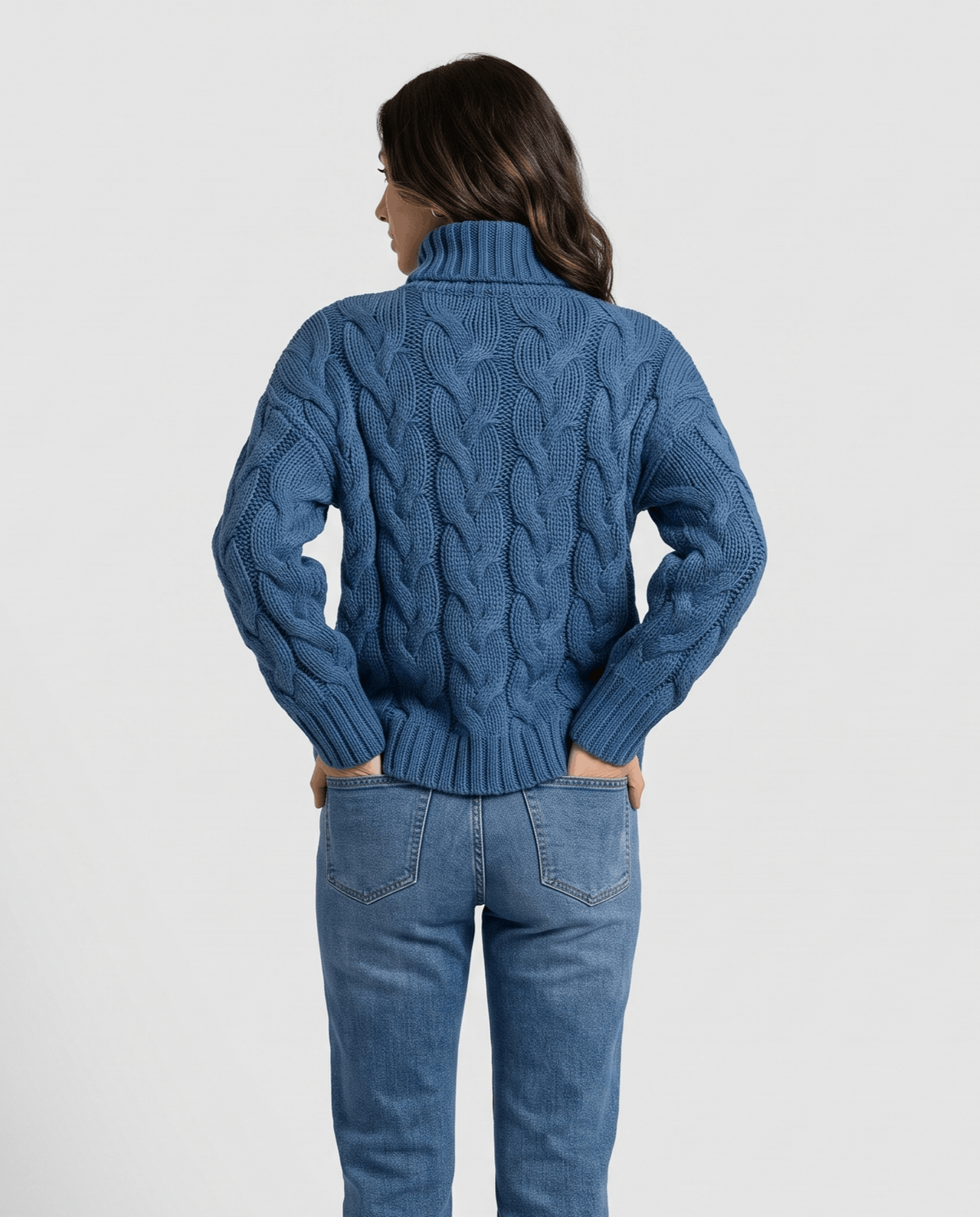 Back view of blue chunky knit sweater with hands in back jeans pockets