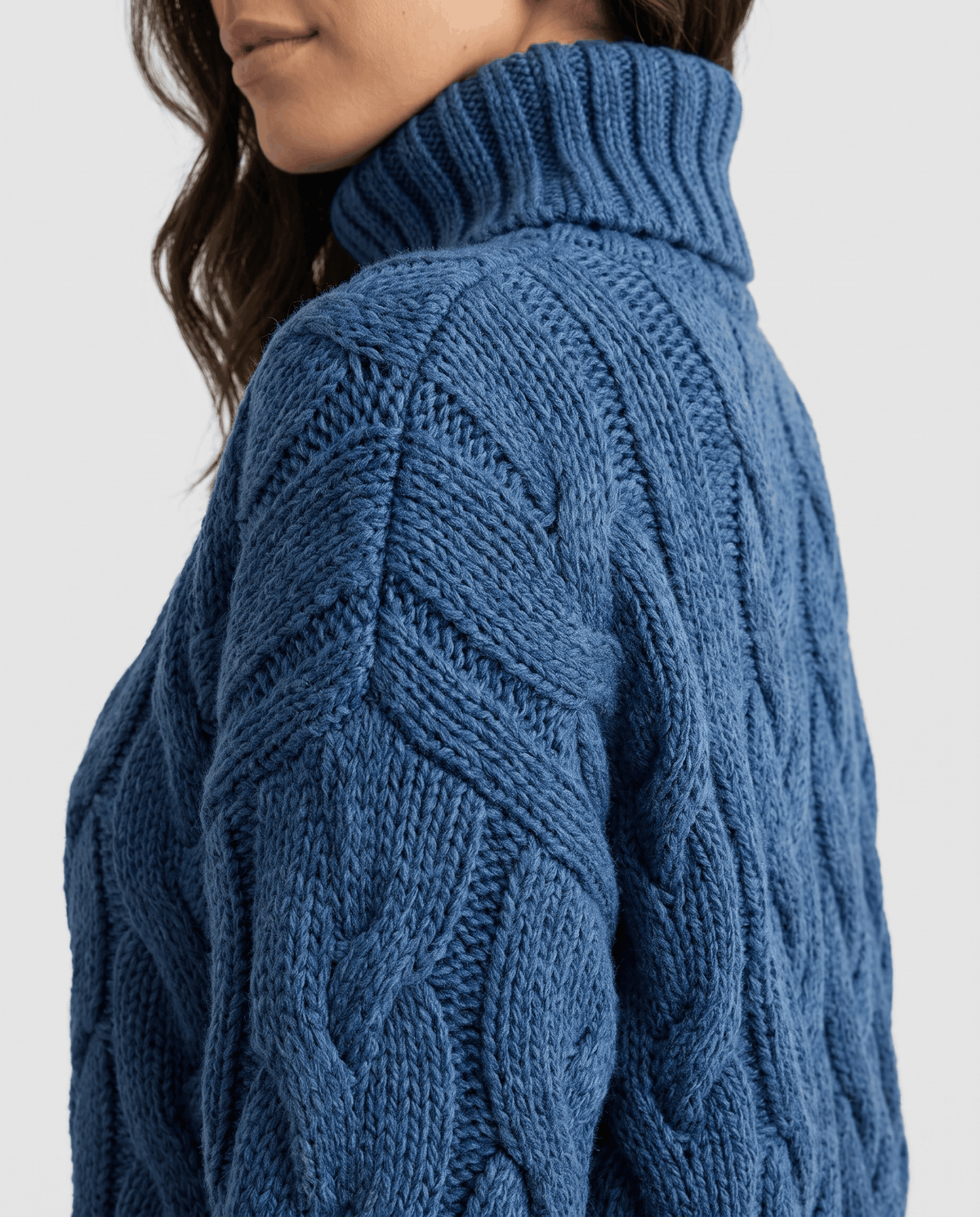 Side shoulder detail of blue cable knit with tall ribbed turtleneck