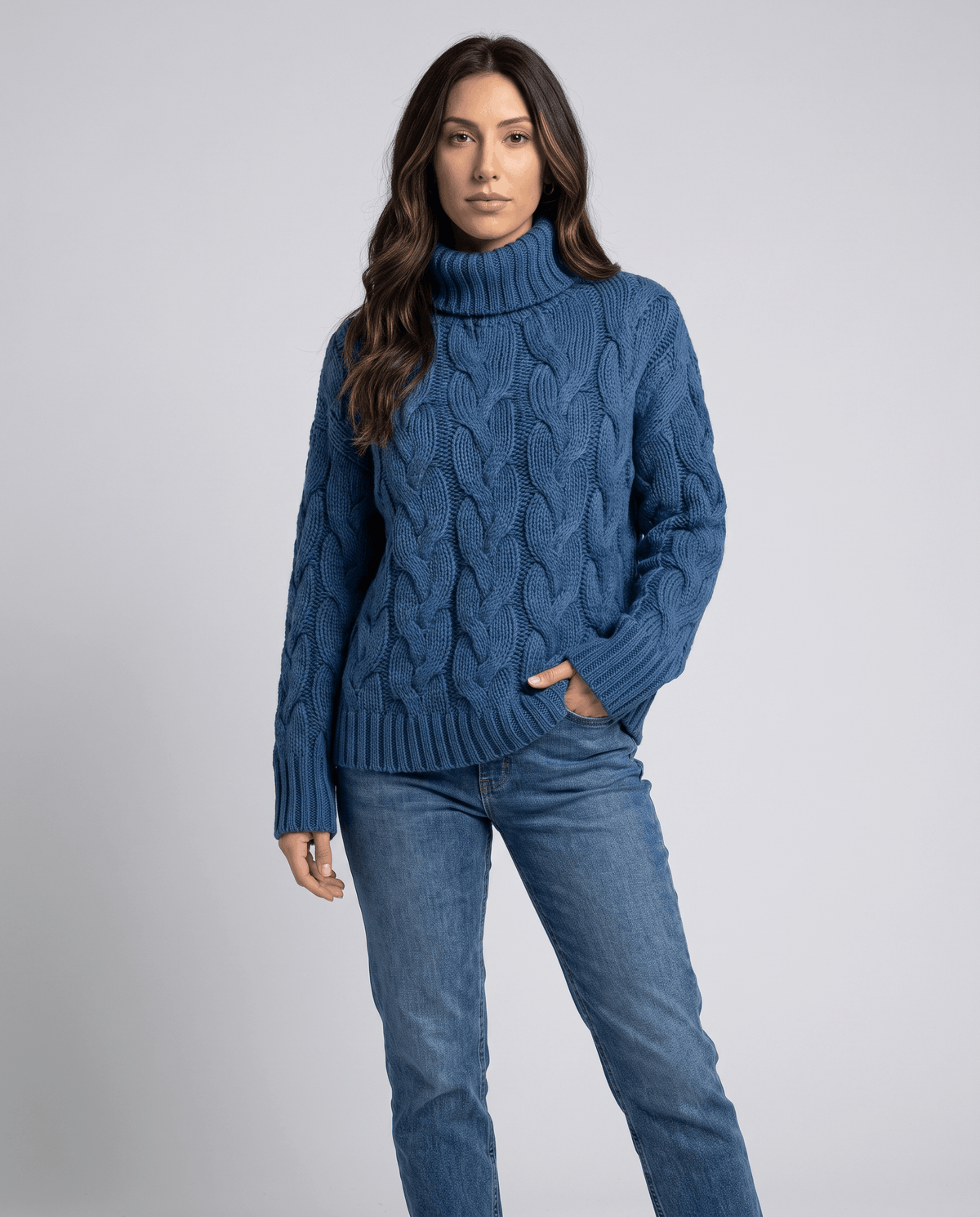 Front view of blue cable knit turtleneck styled with light wash jeans