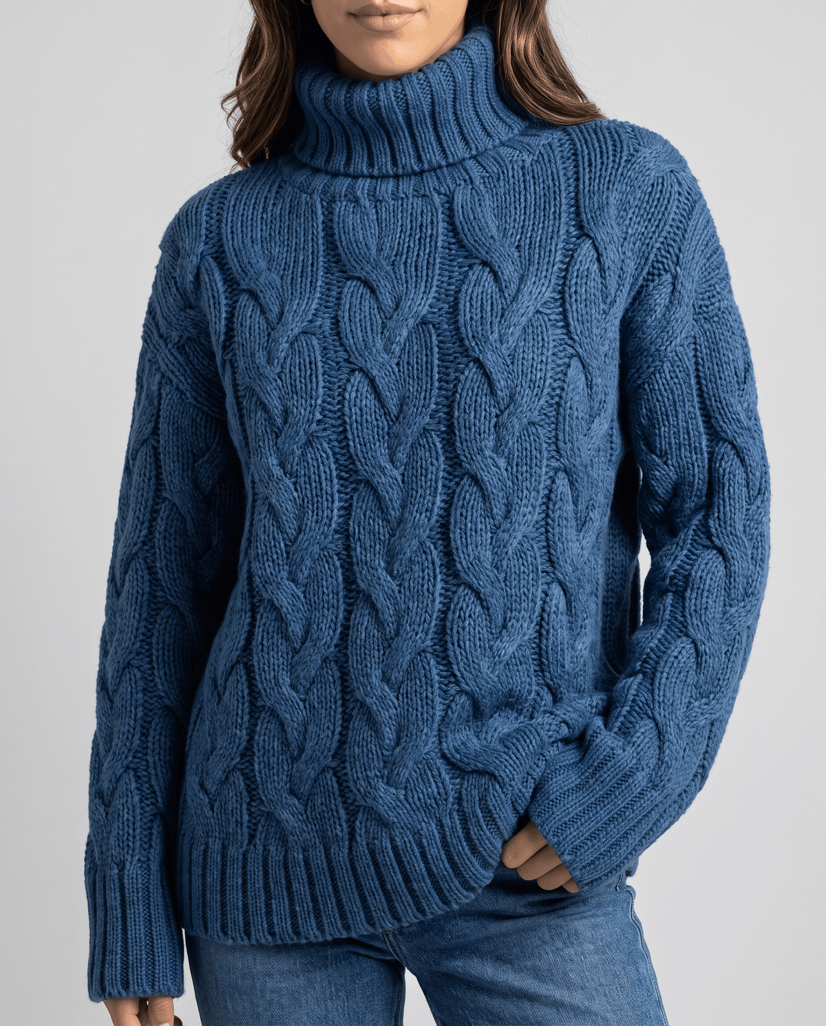 Cropped front view of blue braided cable sweater with ribbed cuffs and hem