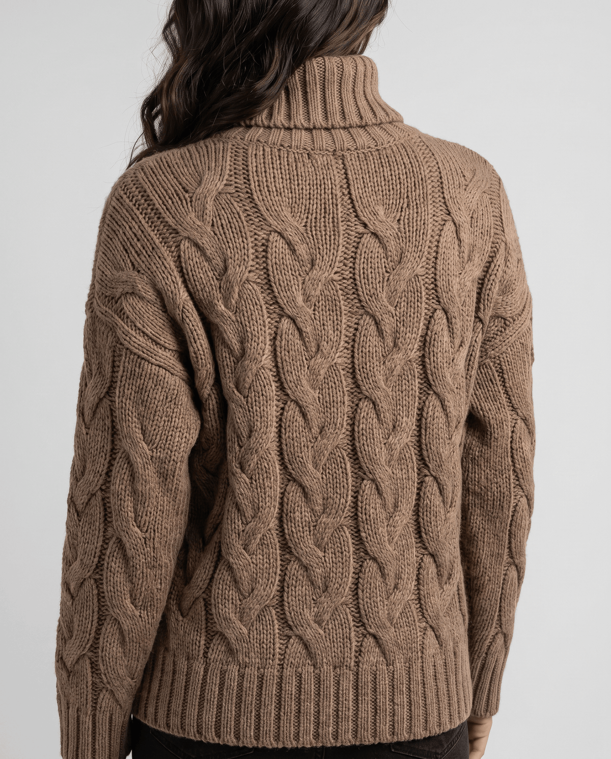 Back view of brown cable knit sweater showing vertical braids and ribbed hem