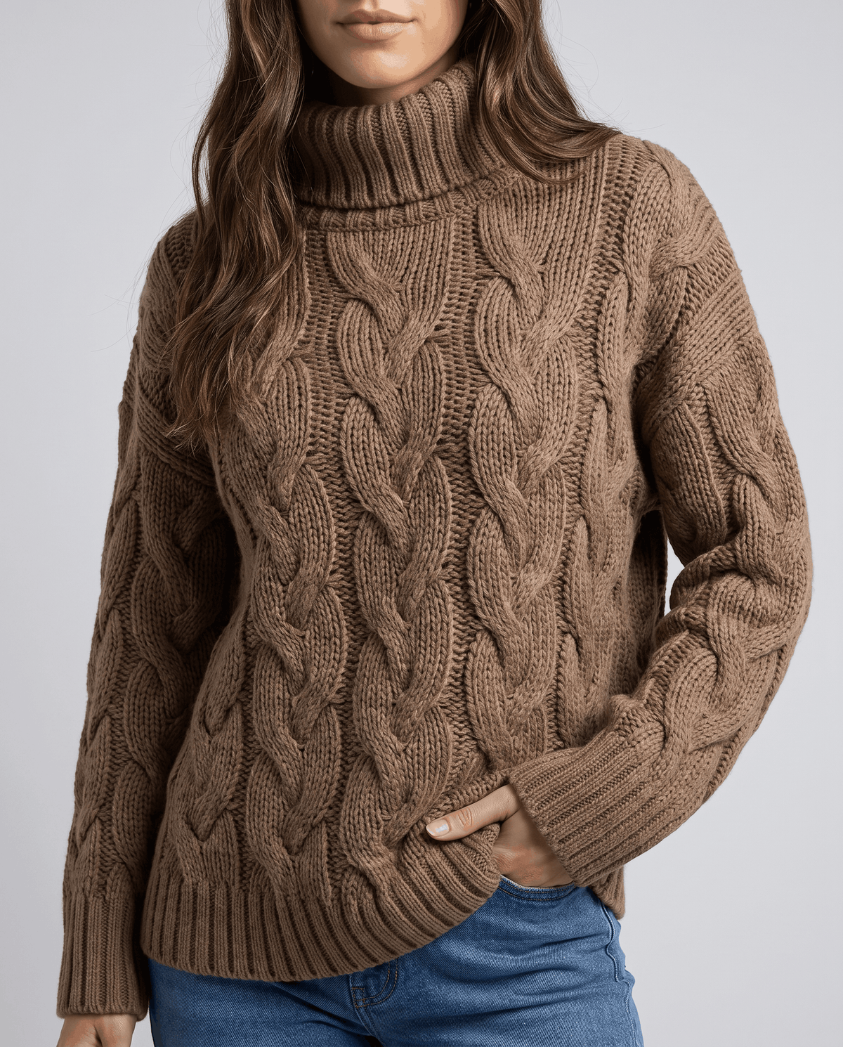 Cropped front view of brown cable knit turtleneck with hand in jeans pocket