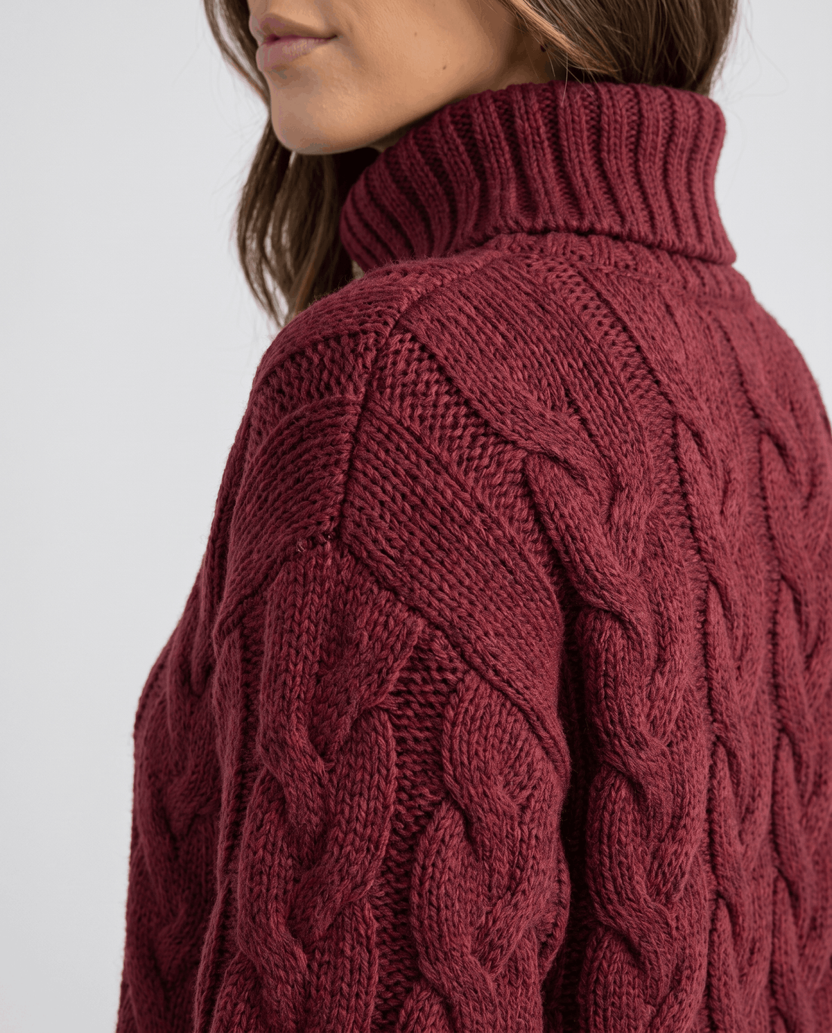 Shoulder detail of burgundy knit showing cable braids and ribbed collar