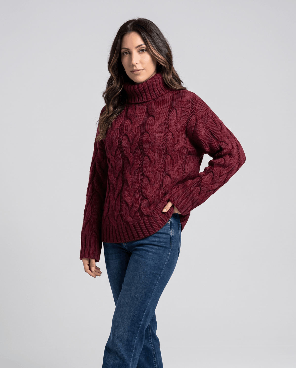 Three-quarter view of burgundy turtleneck sweater styled with blue jeans