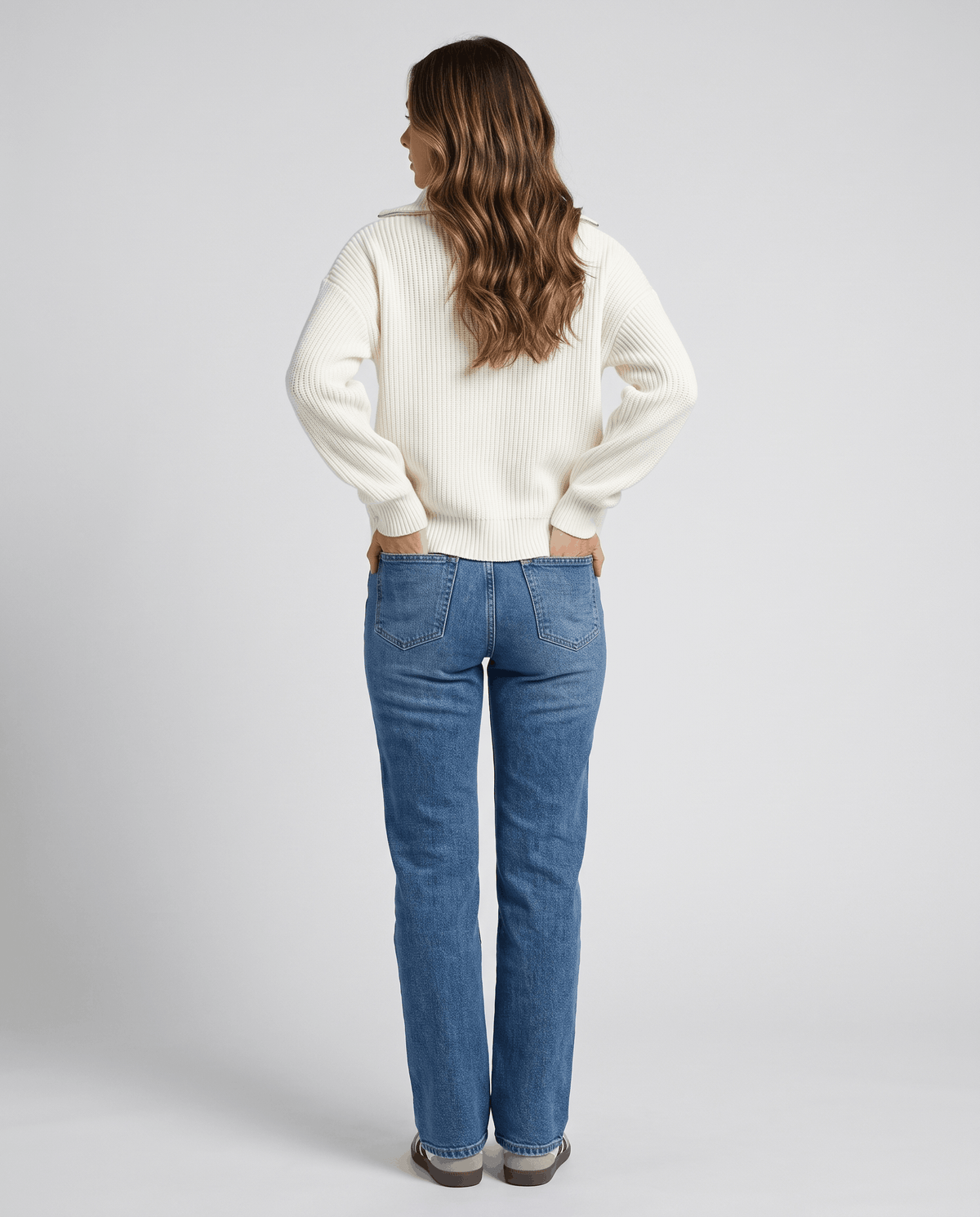 Back view of white half-zip sweater with straight-leg blue jeans