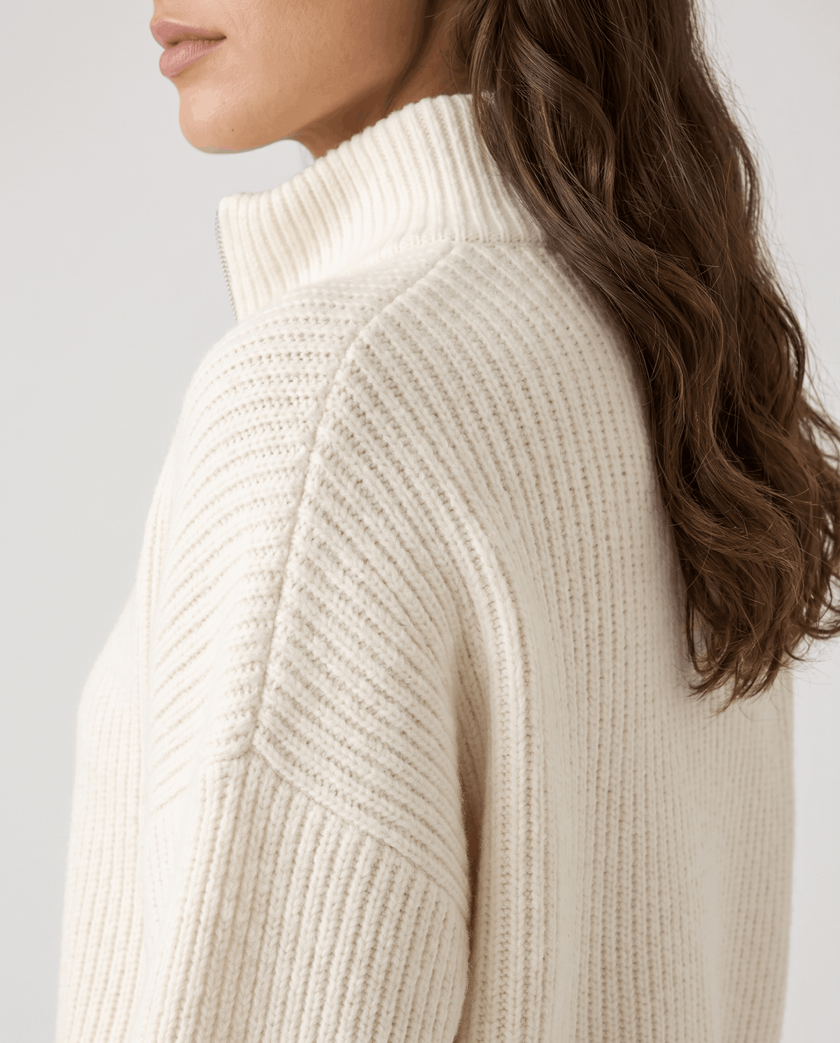 Side view of the zipped-up stand collar on a warm white sweater