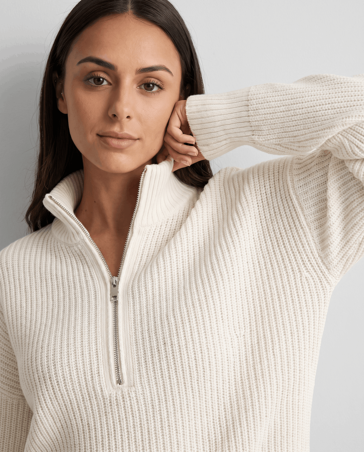 Close-up of model touching her neck beside the white sweater's half zip