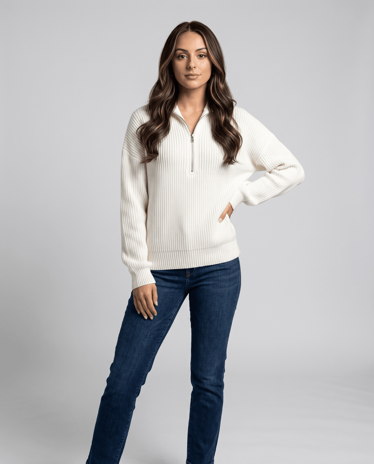 Full-length view of white half-zip sweater with blue jeans, hand on hip