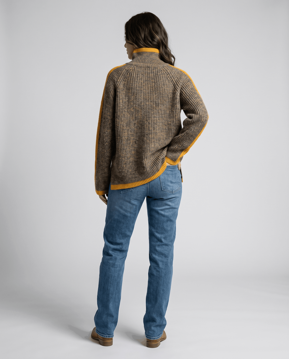Full-length back view of brown oversized sweater worn with light wash jeans