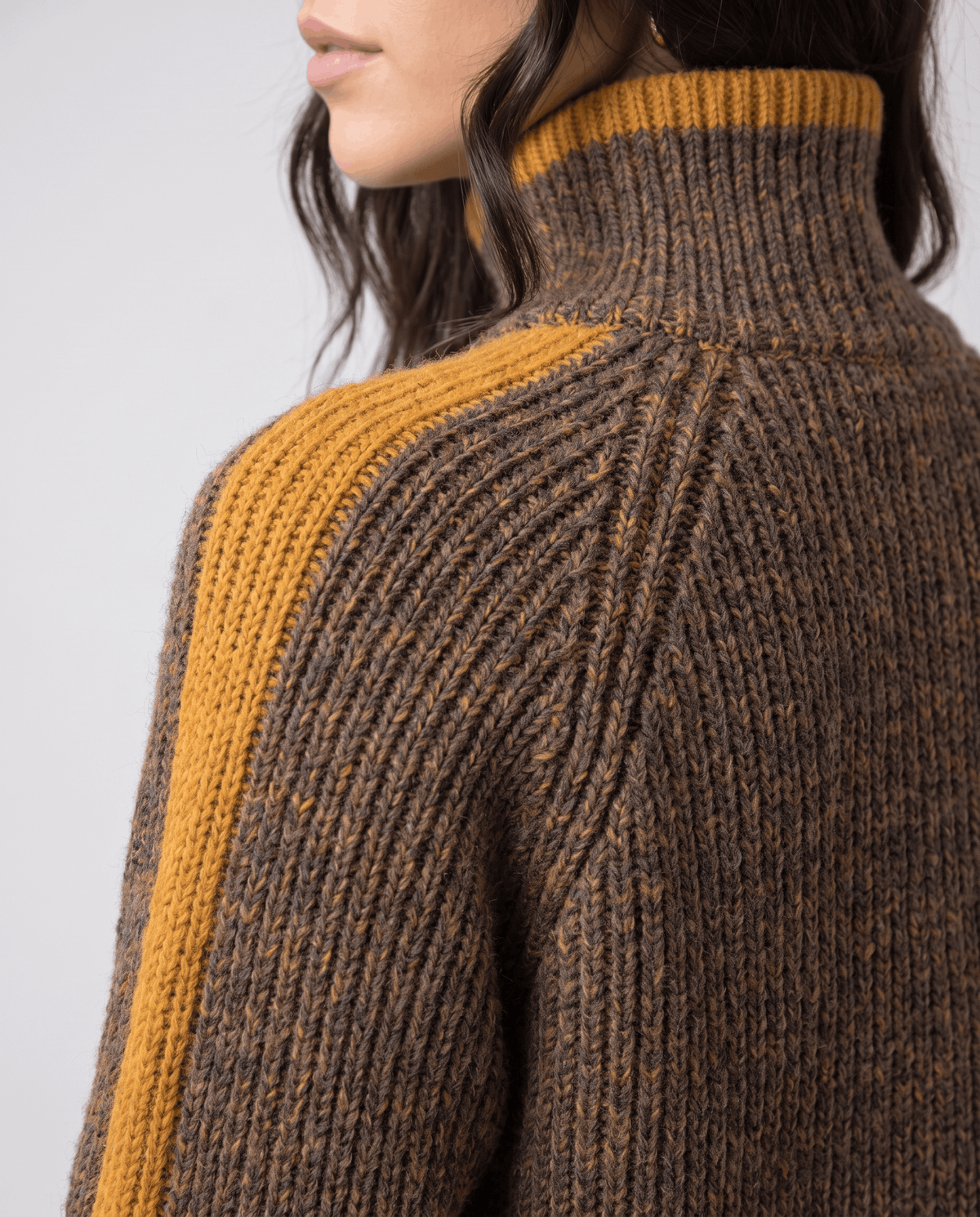 Shoulder detail showing raglan seam and mustard stripe on a marled brown sleeve
