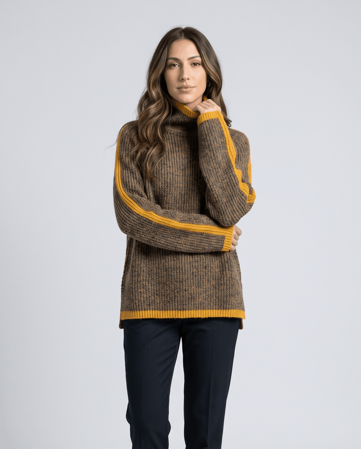Woman wearing a brown contrast trim turtleneck sweater with navy trousers, hand at collar