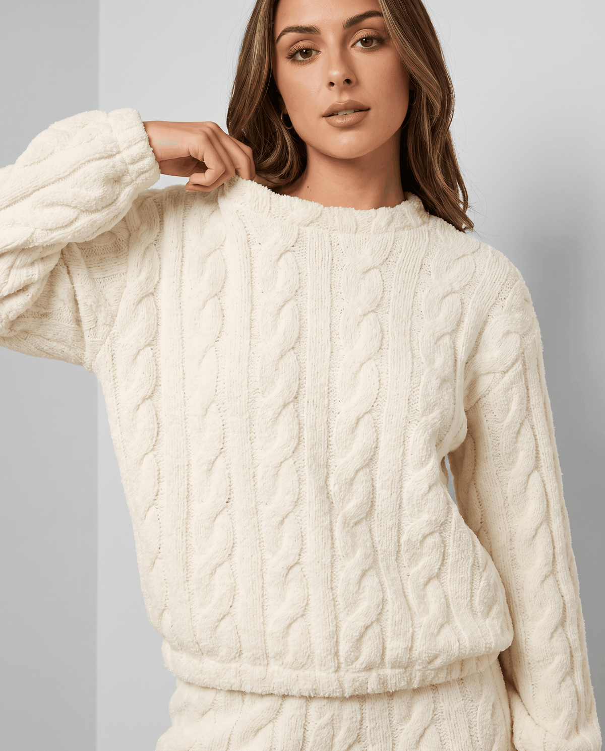 Woman in a cream jacquard crew neck top with long sleeves and a plush texture