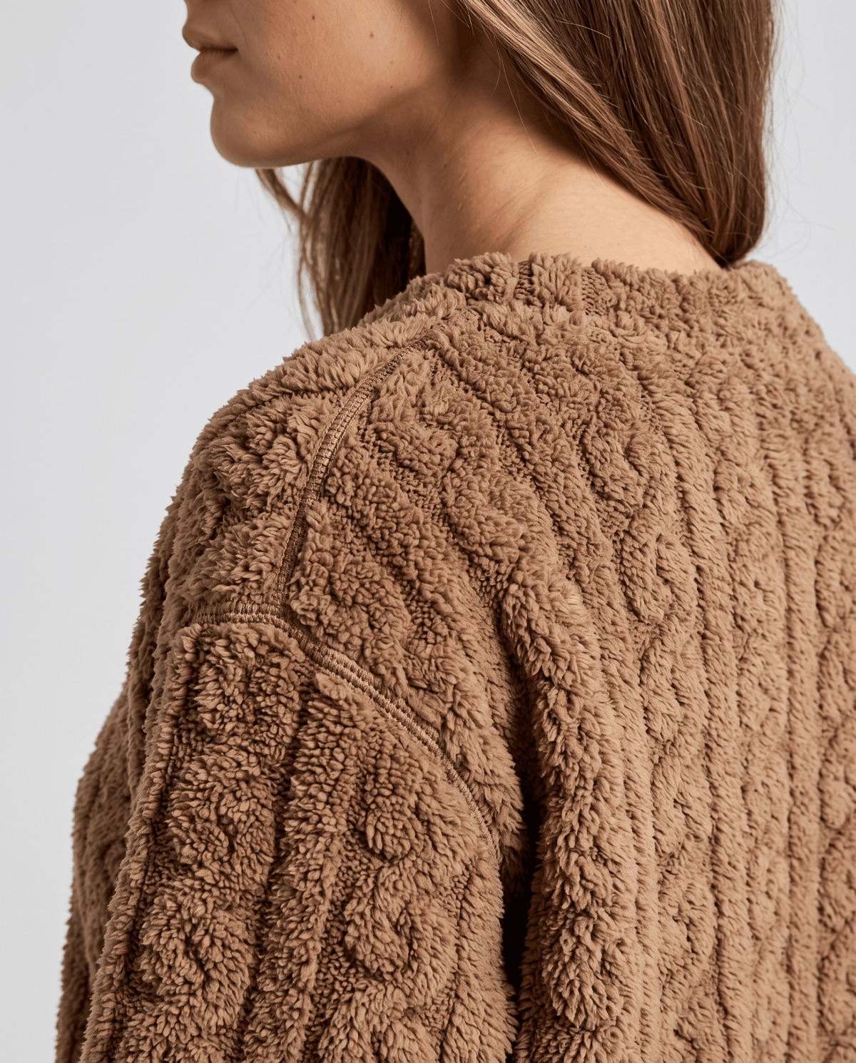 Close-up of tan jacquard texture on the sleeve and shoulder of a plush top