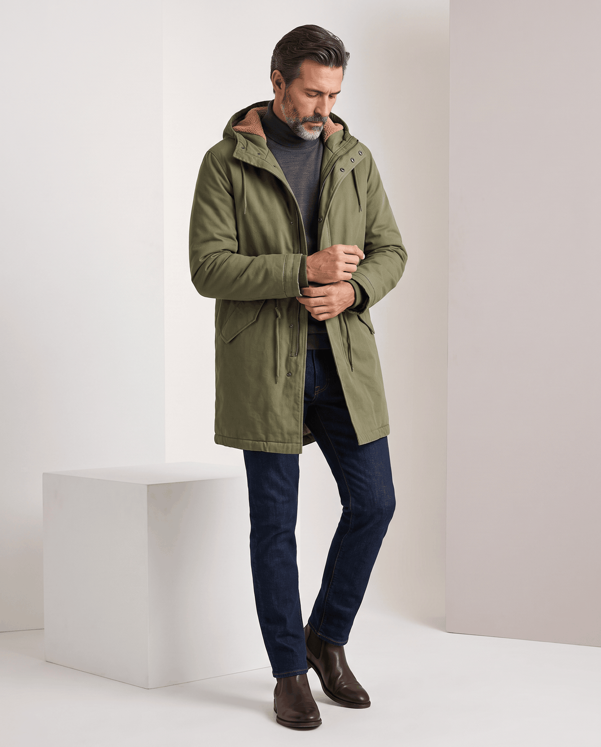 Men's army green cotton hooded parka, full-length view while zipping up
