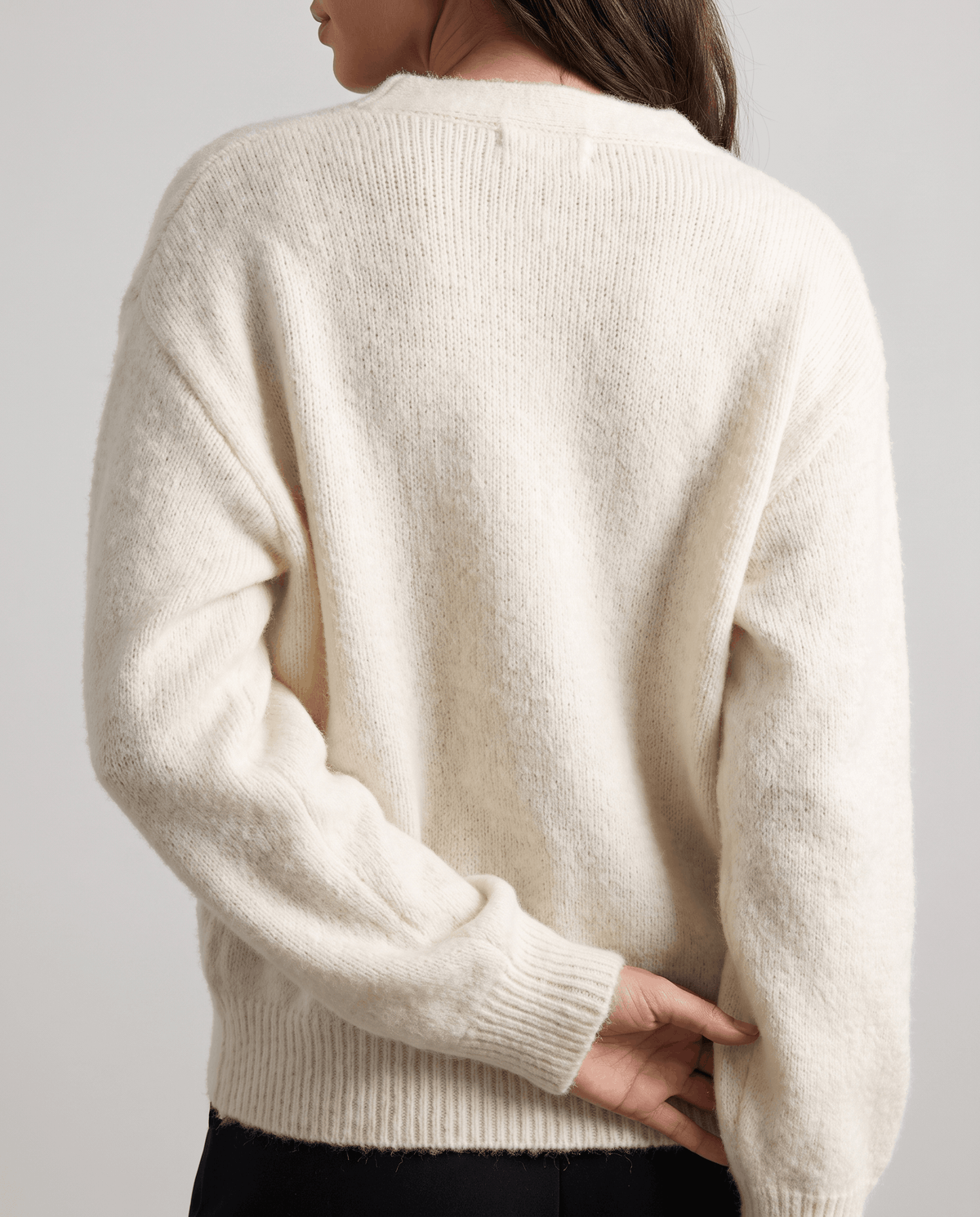 Back view of the beige plush knit cardigan with ribbed hem