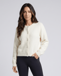 Women's crew neck cardigan sweater in beige with black pants and hand in pocket