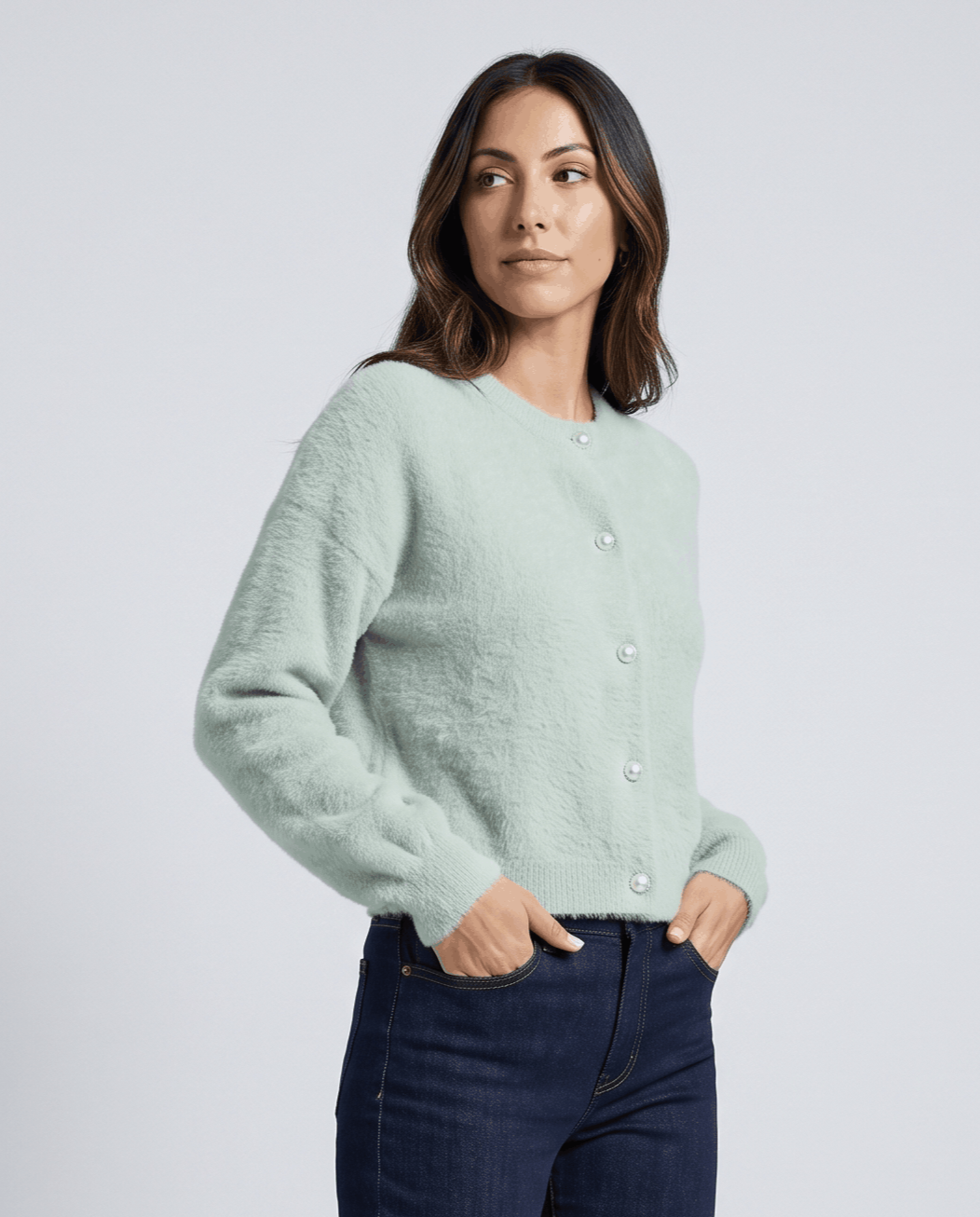 Sage green cardigan worn with dark jeans and hands in front pockets